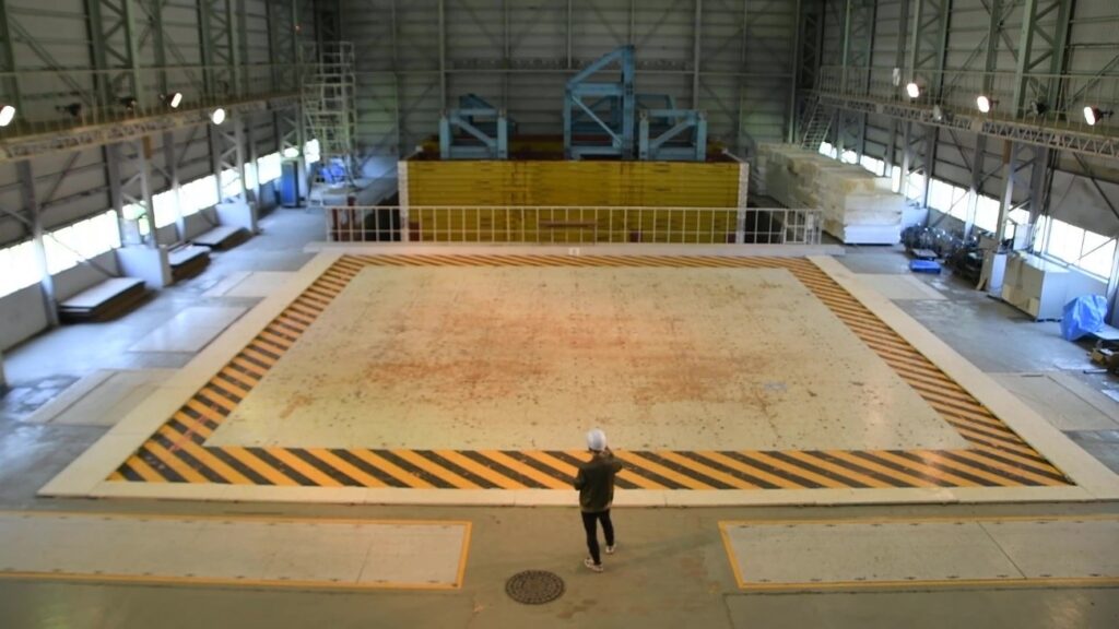 Large-Scale Earthquake Simulator where full-scale vibration tests are conducted:
 the size of the facility can be seen by comparing it with the figure in the center